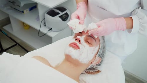 Doctor Cosmetologist Carefully Wiping Face of Woman Client During Skincare Session Professional