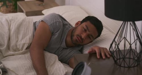 Young Man Wakes Up and Turns Off Alarm