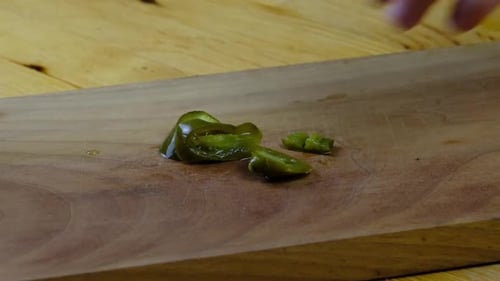 the chef is cutting green pickled hot peppers on a cutting board