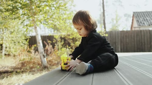 Happy Toddler Playing with Toy Truck Outdoors