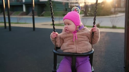 Toddler Enjoying a Swing at a Playground During Sunset in a Vibrant Outdoor Setting A Young Child