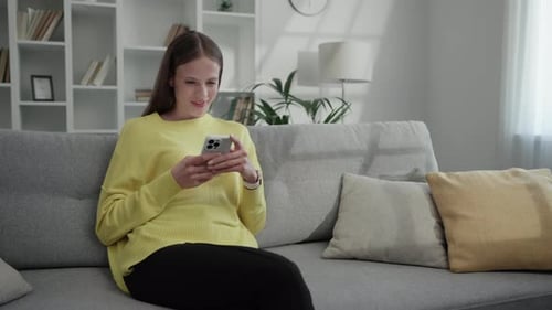 Young Woman Using Smartphone on Sofa at Home