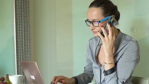 Businesswoman working on computer and talking on phone