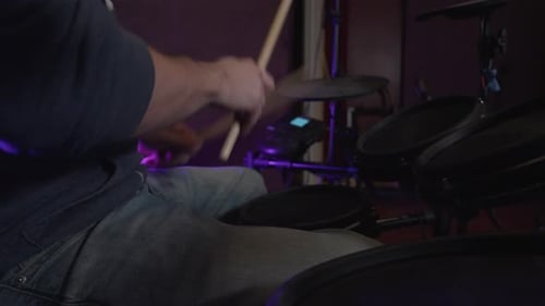 close up side view of a man playing an electronic drum set in a recording studio