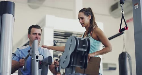 Woman Trainer Helping Man Using Exercise Machine