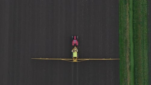Tractor Spraying Pesticides On agricultural field With Sprayer, topdown aerial