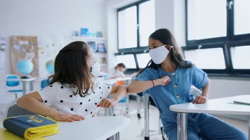Children with face masks greet each other back at school after covid-19 lockdown