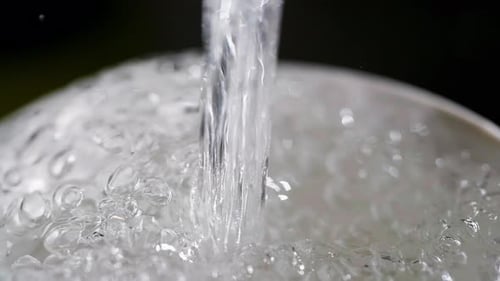 Close up of a running dripping tap. Water flowing and bubbling. Tap water silver kitchen fixtures,