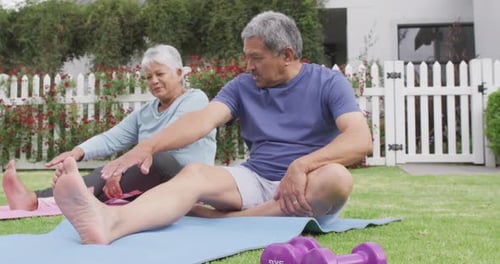 Happy senior diverse couple practicing yoga in garden