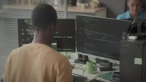 Male Programmer Working on Computer with Dual Monitor in Office