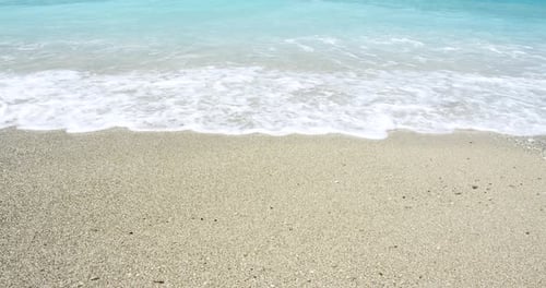 Close up of foaming waves and splashes on sandy beach sunshine. Concept of wild natural relaxation