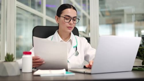 Young Woman Doctor Working at Desk with Laptop