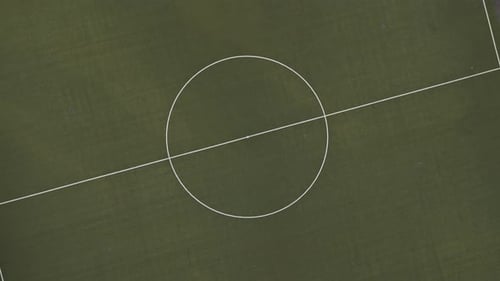 Top Down View with rotation of an empty, green football field in the middle of the forest, Drone Foo