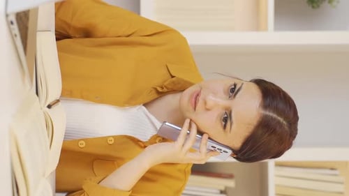 Woman Talking on Mobile Phone at Desk