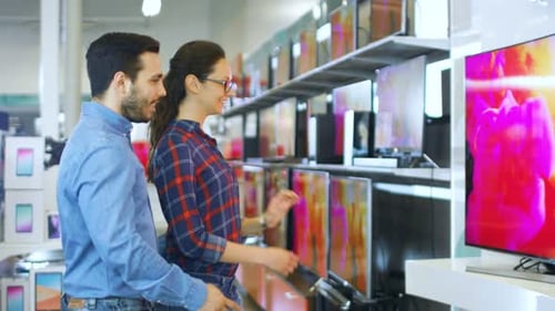 Young Couple Shopping for a New 4K UHD Television Set in the Electronics Store. They're Deciding on