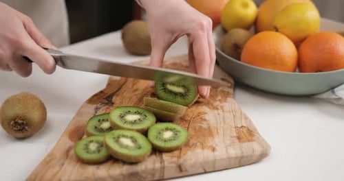 Hands Slicing Fresh Kiwi Fruit with Knife