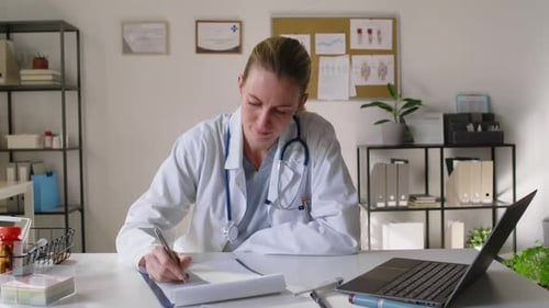Portrait of Middle-Aged Caucasian Female Doctor Working at Desk in Clinic