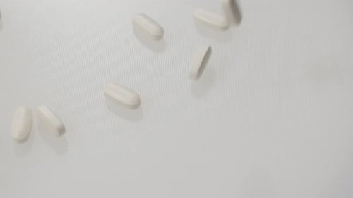 Pills Falling on a Clean, Light Gray Surface