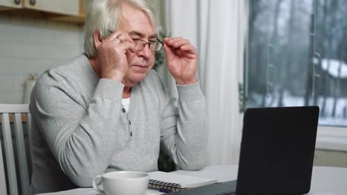 Senior Man Using Laptop in Bright Home Kitchen