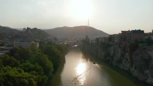 Aerial view of a river in downtown Tbilisi, Georgia at sunset, sunrise with mountains in the backgro