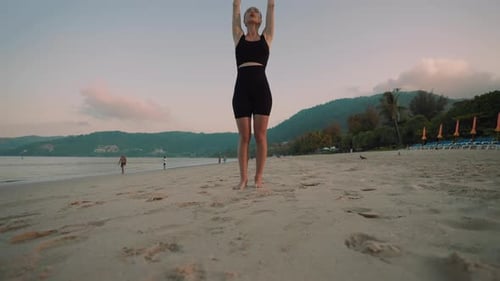 Barfüßige Frau macht Yogaübungen Lounge Warrior posiert am Sandstrand am Meeresstrand bei Sonnenuntergang weiblich