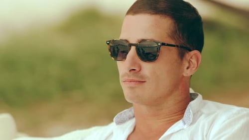 Beautiful Young Caucasian Couple Cuddling, Smiling and Talking on the Beach, Looking