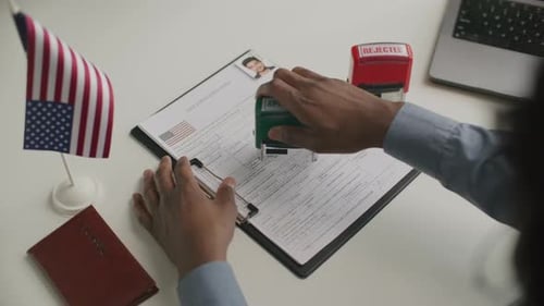 Close-Up of Visa Officer Stamping Approval on Application Form