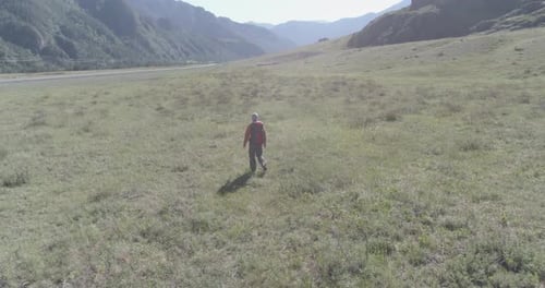 Flight Over Backpack Hiking Tourist Walking Across Green Mountain Field Huge Rural Valley at Summer
