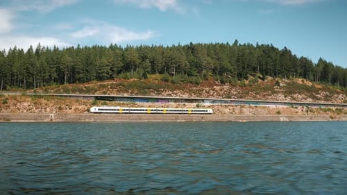 Fast passenger train driving on railroad along mountain lake