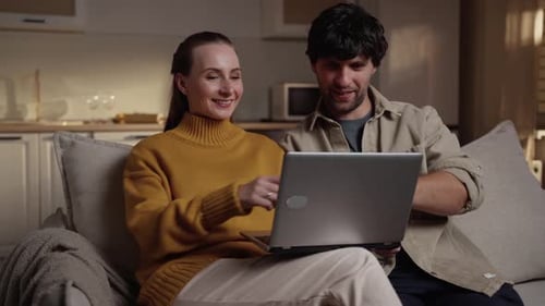 Couple Using Laptop Together on Comfortable Sofa