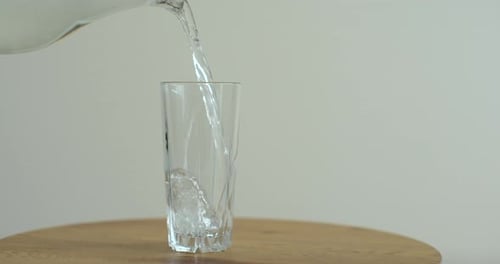Close Up of Cold Drink Pours Into a Glass Pouring Clean Fresh Water in Transparent Glass Slow Motion