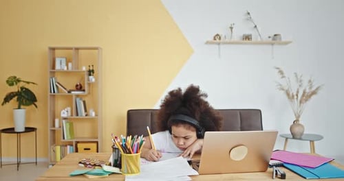 Child Doing Homework at Desk with Laptop