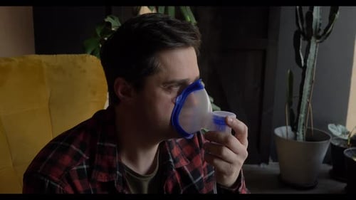 un homme blanc d'âge moyen enrhumé inhale des médicaments à travers un nébuliseur à la maison