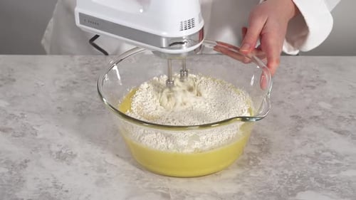 Nahaufnahme: Mischen der Zutaten in einer Glas-Rührschüssel, um den Funfettti-Bundt-Kuchen zu backen
