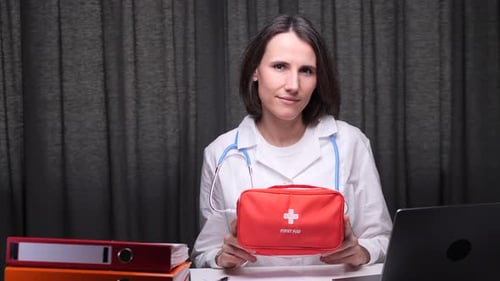 Female Doctor Holding First Aid Kit in Medical Office
