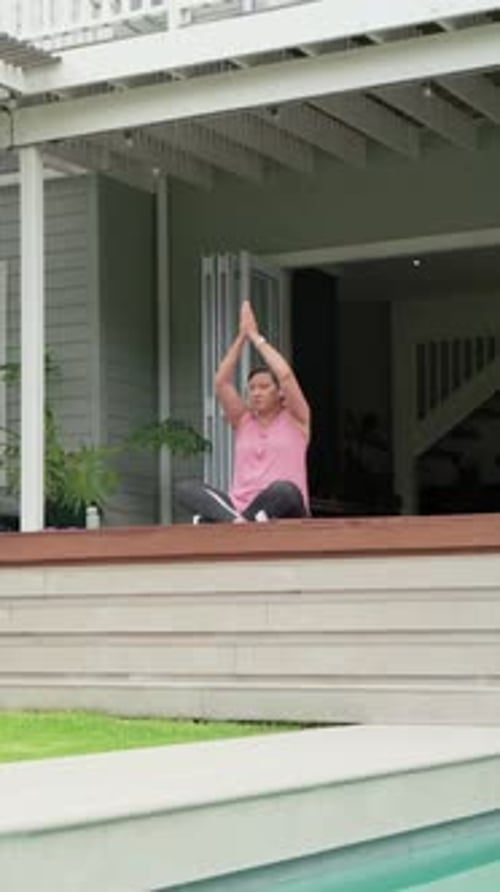 Vídeo vertical: levantando os braços estendidos, mulher de blusa rosa se movendo para namaste para ioga no convés com tapete