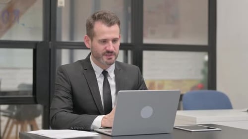 Businessman Engaged in Video Call at Desk
