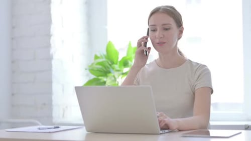 Woman Working on Laptop Answering Phone
