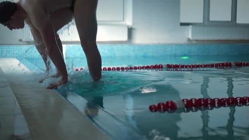 Vista lateral Jovem emergindo da piscina se afastando em Câmera lenta