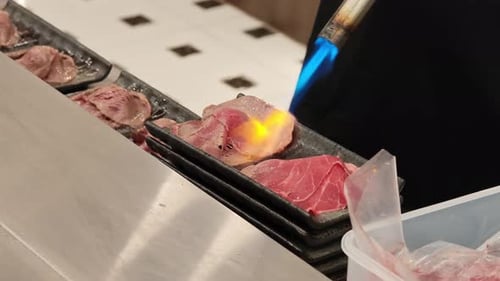Chef Torching Slices of Meat in Restaurant Kitchen