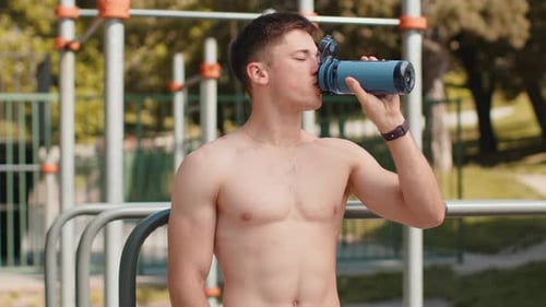 Shirtless Man Drinks Water After Outdoor Workout