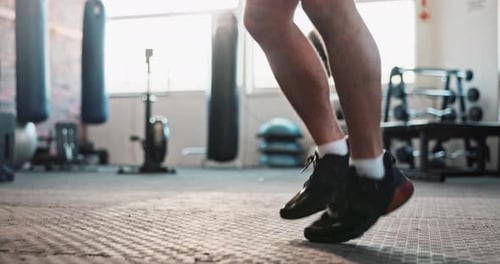 Legs jumping, skipping rope or man in gym with fitness for health, training