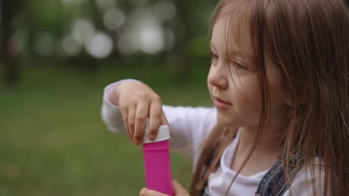 Smiling Girl Blowing Bubbles in a Green Meadow