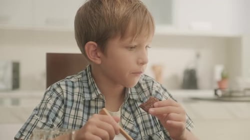 Boy Eating Cereal and Chocolate in Kitchen