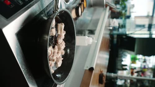 chef in a professional kitchen in a restaurant frying juicy chicken fillet in a pan close-up