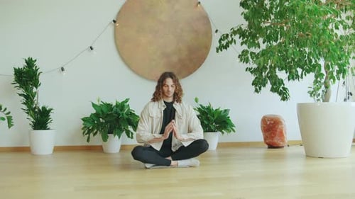 Man Meditating Peacefully Indoors Surrounded by Greenery