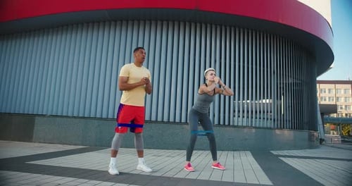 Couple Doing Resistance Band Squats Together Outside