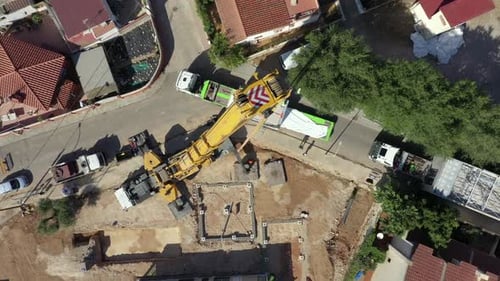 Vista aérea sobre una gran grúa amarilla en una obra de construcción, espiral ascendente.