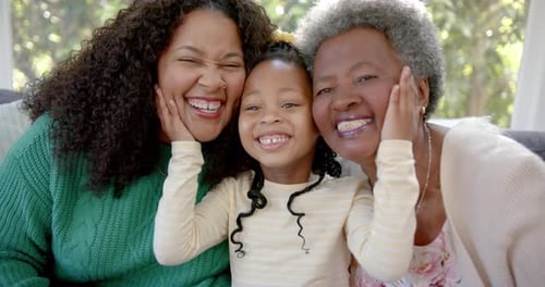 Portrait of african american mother, daughter and grandmother smiling in sunny room, slow motion
