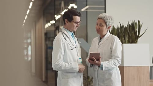 Doctors Looking at Digital Tablet and Having Discussion in Hospital